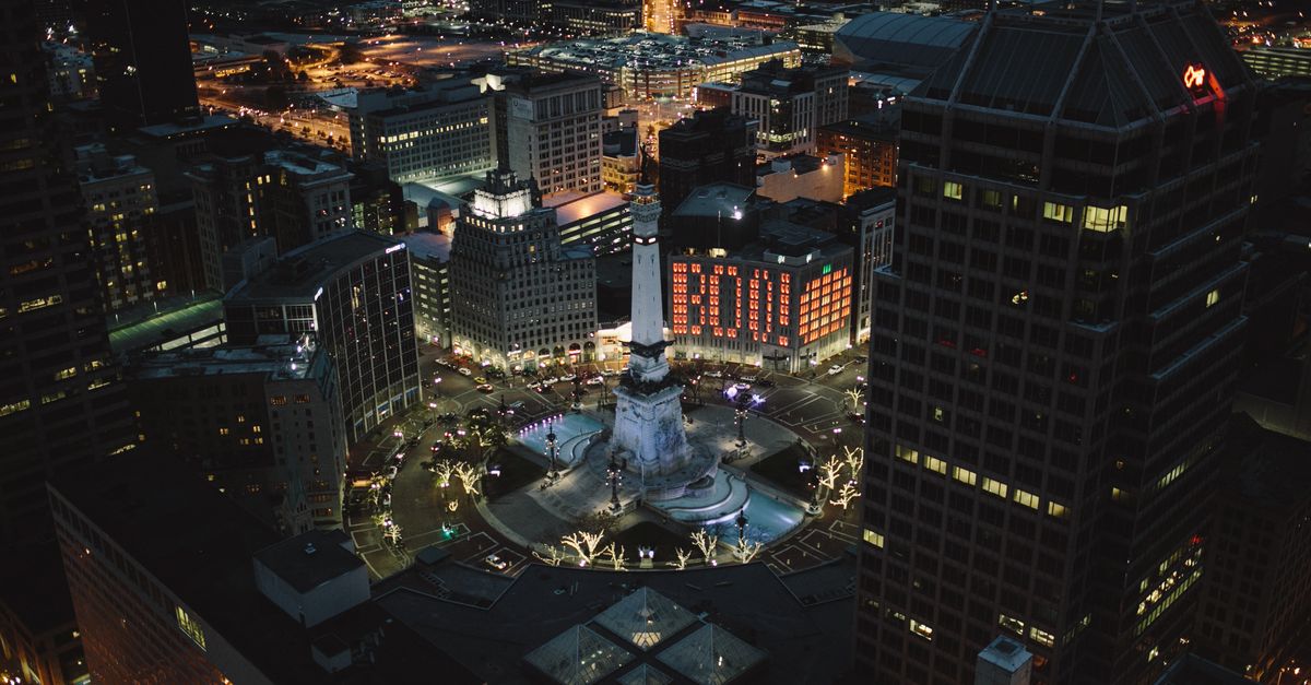 Stunning aerial night view of Monument Circle in Indianapolis, showcasing city lights and architecture.